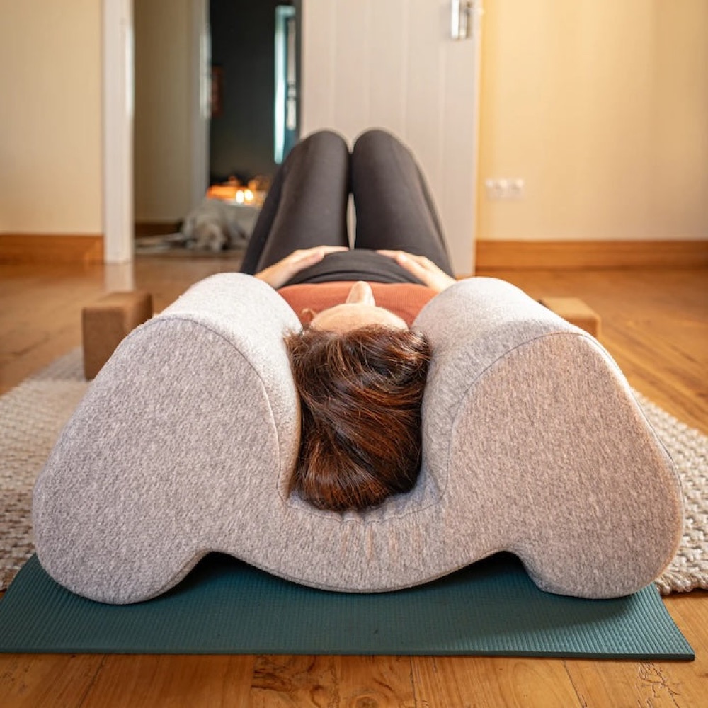 A person lying with their head nestled between the arms of the Drop Pillow
